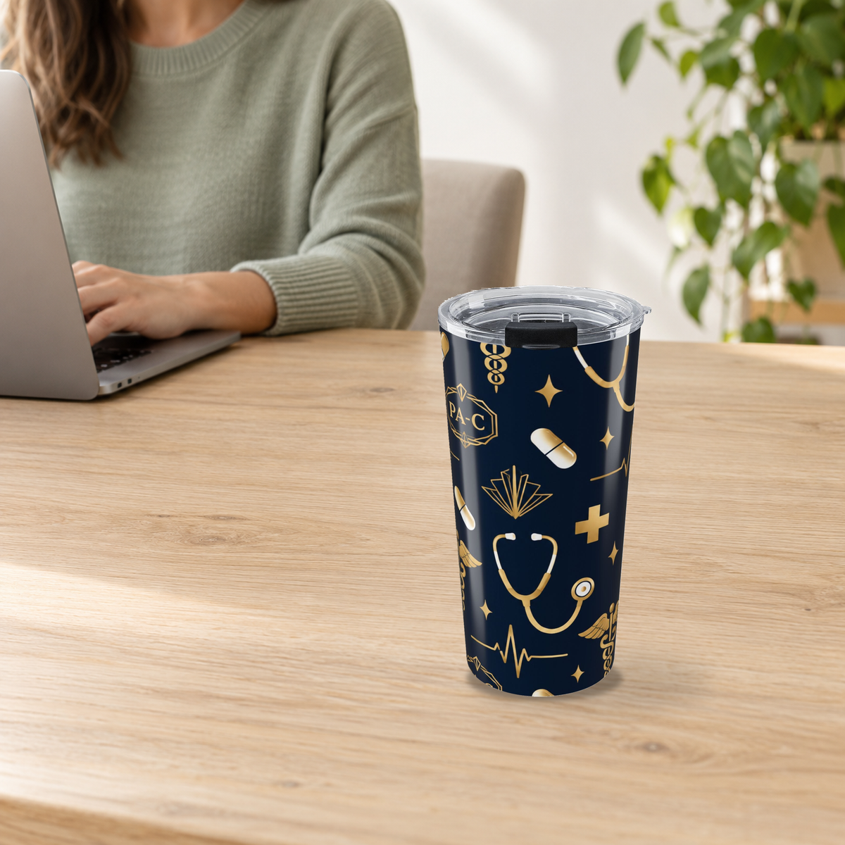 PA-C Stethoscope and Caduceus Tumbler in the 20oz size on a wooden desk beside an adult using a laptop