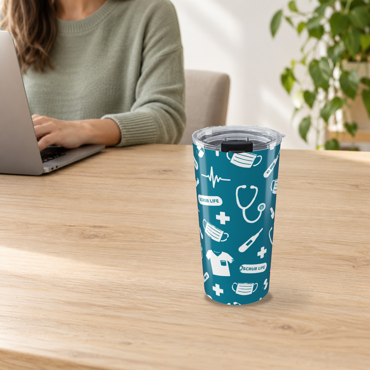 Scrub Life Medical Pattern Tumbler in the 20oz size on a wooden desk beside an adult using a laptop