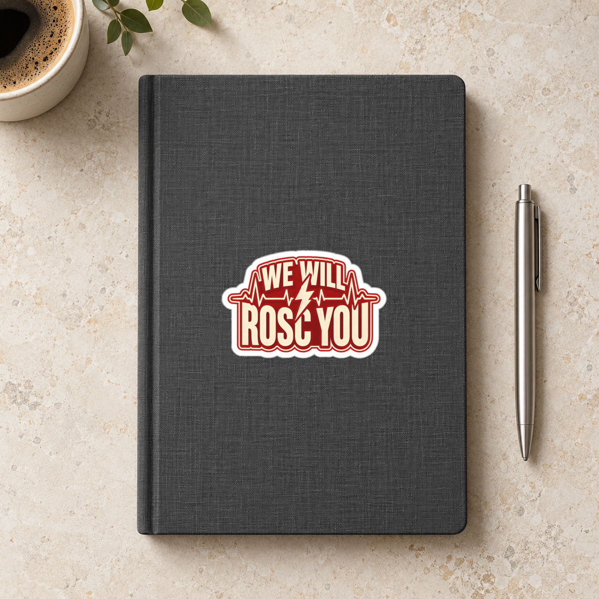 We Will ROSC You Sticker in the 3 × 3 inch size shown on a charcoal notebook in an illustrative lifestyle mockup