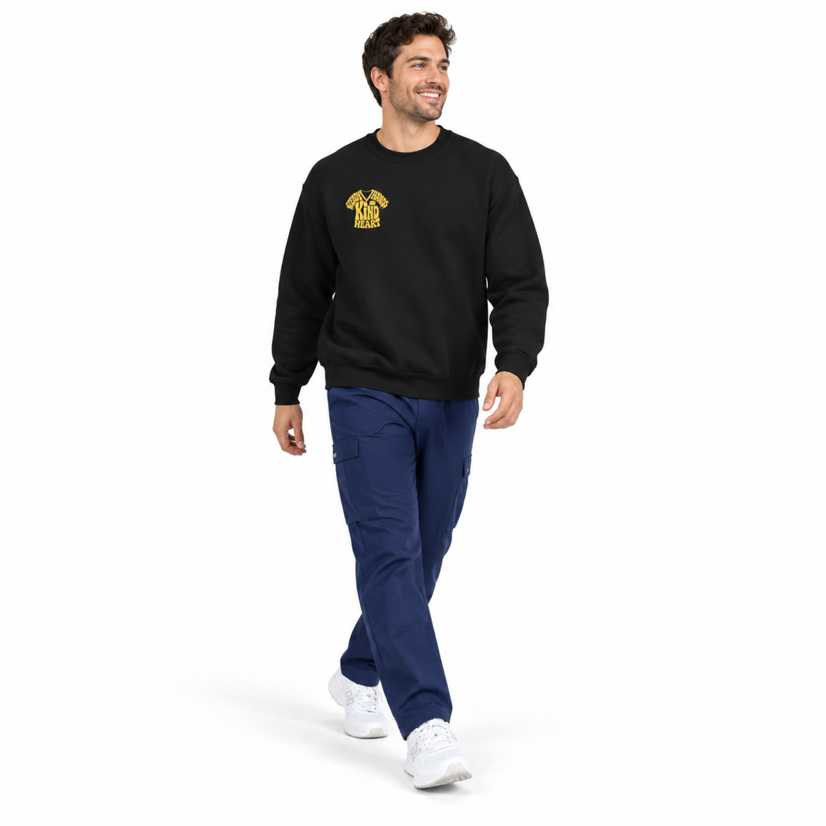 Medical professional wearing black Steady Hands Kind Heart sweatshirt with navy scrubs on white background