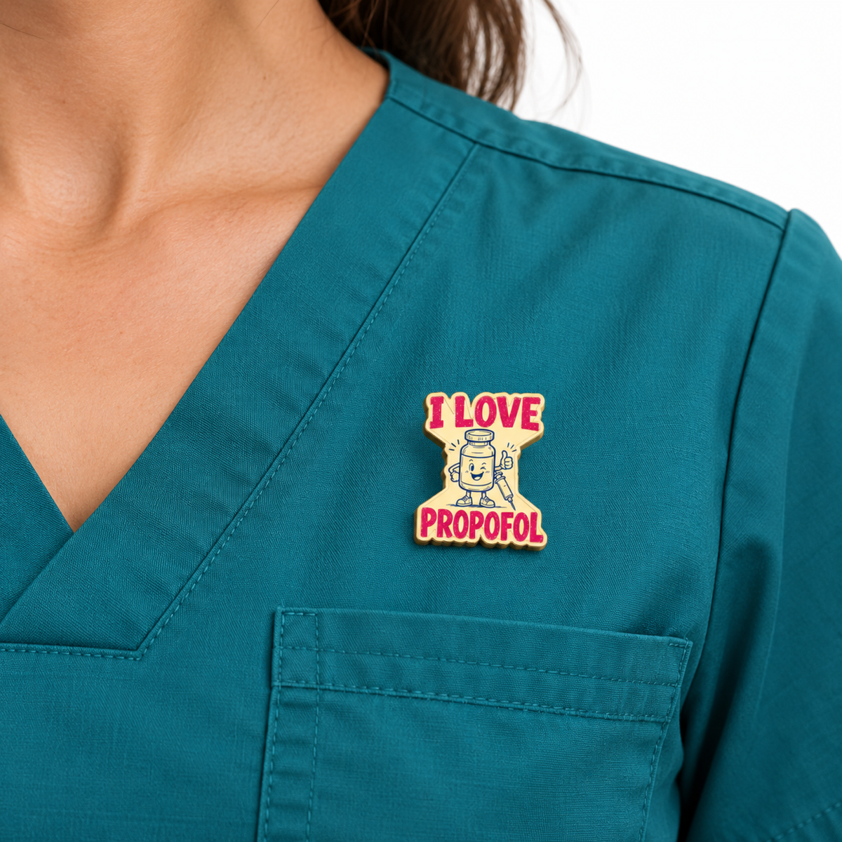 I Love Propofol gold-plated metal pin worn above a teal scrub pocket against a white studio background