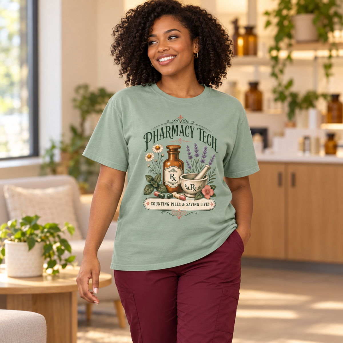 Pharmacy technician wearing a Bay green botanical Pharmacy Tech tee with burgundy scrub trousers in a warm pharmacy staff lounge
