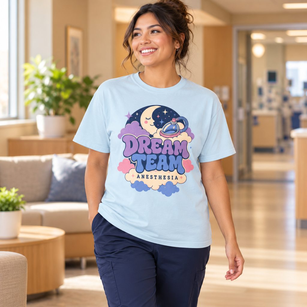 Medical professional wearing a Chambray Dream Team Anesthesia tee and navy scrub trousers in a warm medical lounge