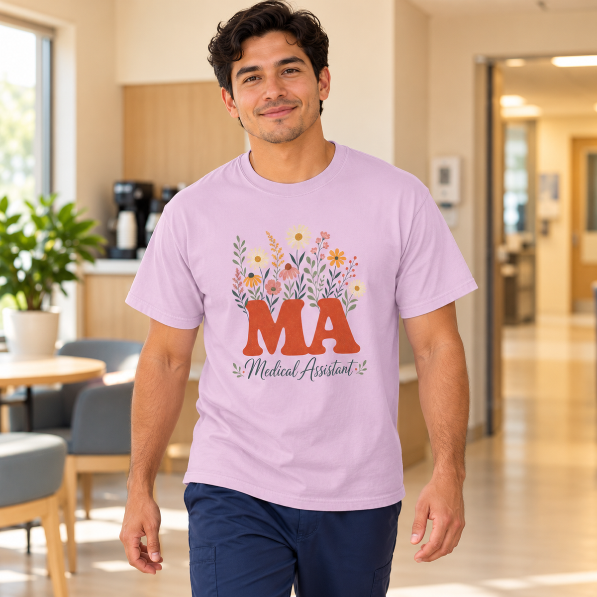 Medical assistant wearing an Orchid purple floral MA tee with navy scrub trousers in a warm clinic staff lounge