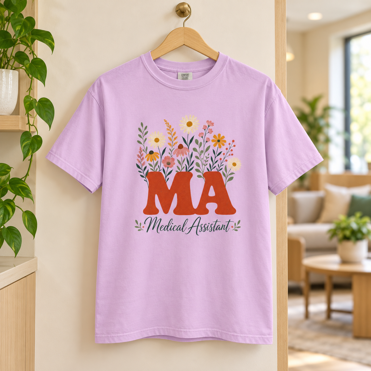 Orchid purple floral Medical Assistant MA tee on a wooden hanger in a warm clinic staff lounge