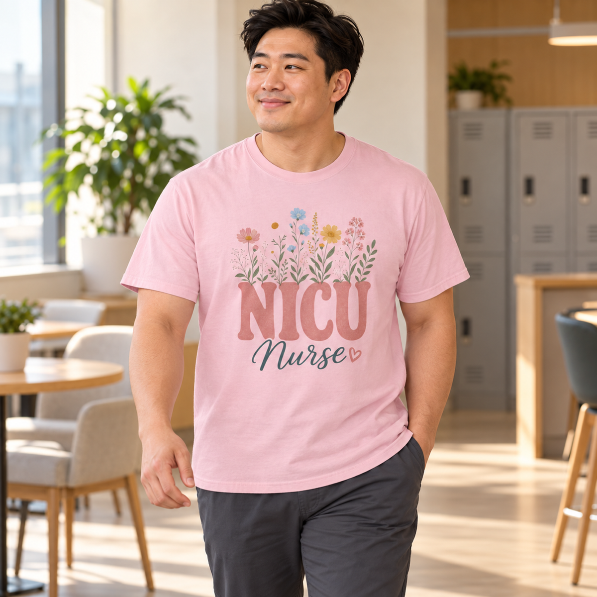 NICU nurse wearing a Blossom pink pastel wildflower tee with charcoal scrub trousers in a warm hospital staff lounge