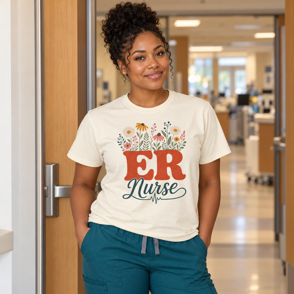 ER nurse wearing an Ivory wildflower ER Nurse tee and teal scrub trousers in a tidy hospital staff entrance