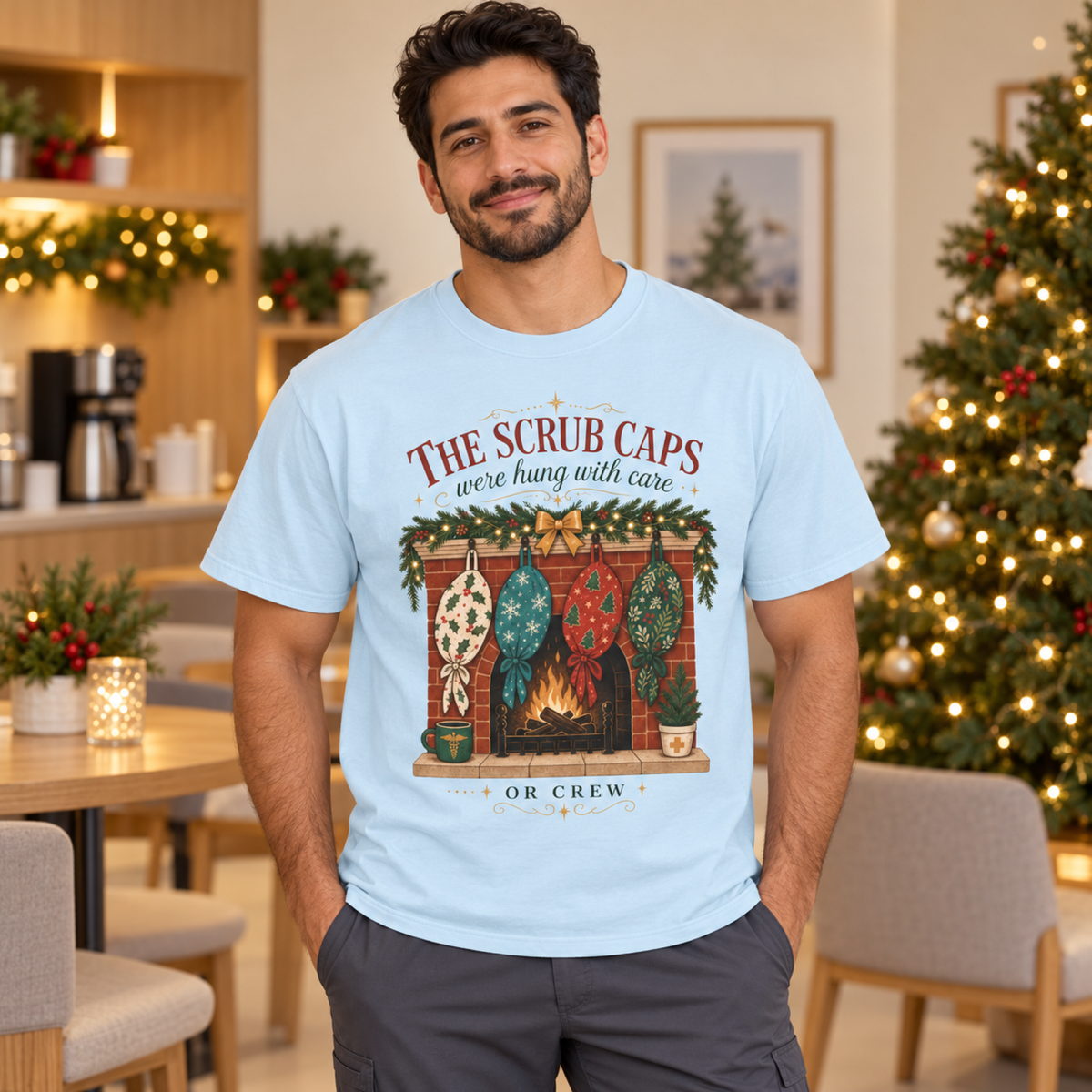 Healthcare professional wearing a Chambray scrub-cap Christmas tee with charcoal scrub trousers in a cozy festive staff lounge