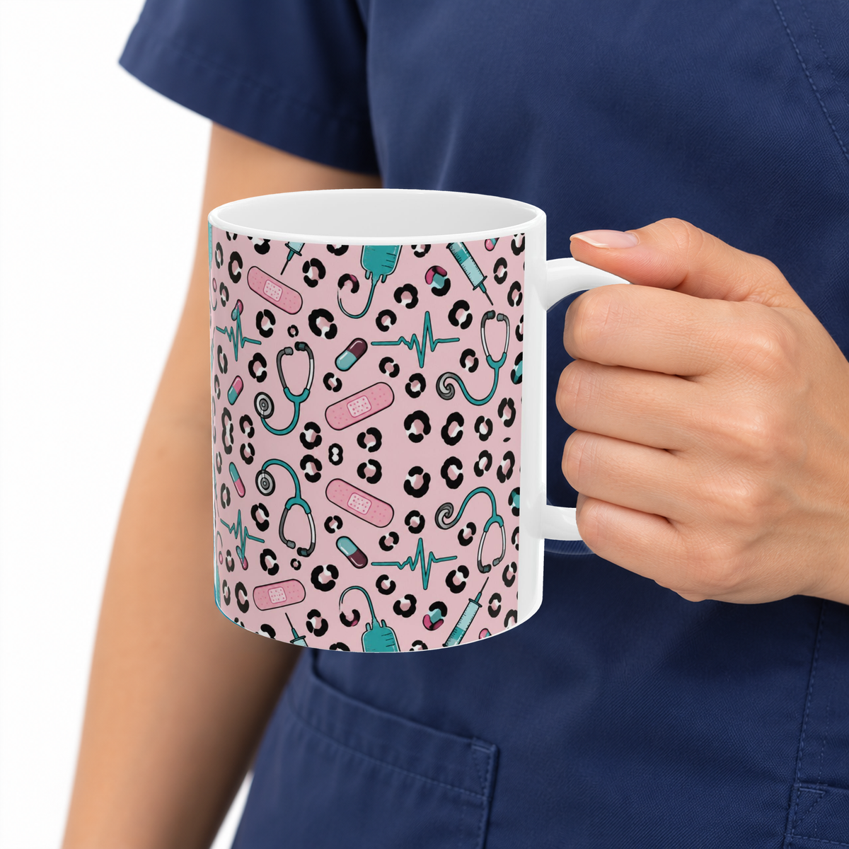Pink Leopard Stethoscope 11oz mug held by a person wearing navy scrubs, showing the original pink, black and teal pattern