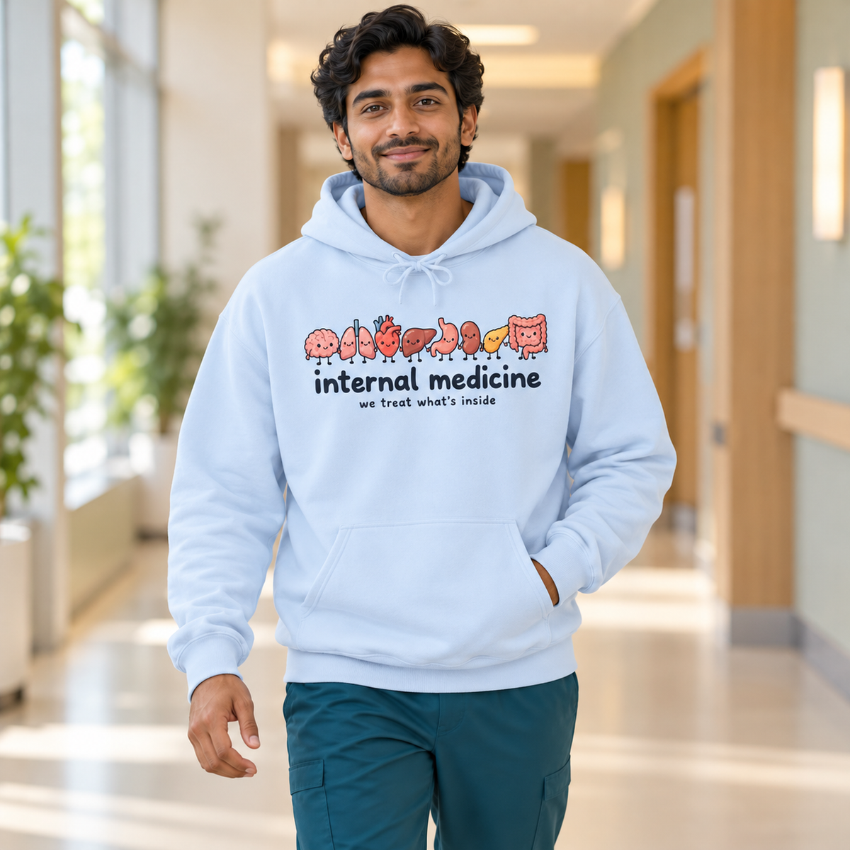 Internal Medicine We Treat What's Inside Hoodie in Light Blue — model in warm medical setting